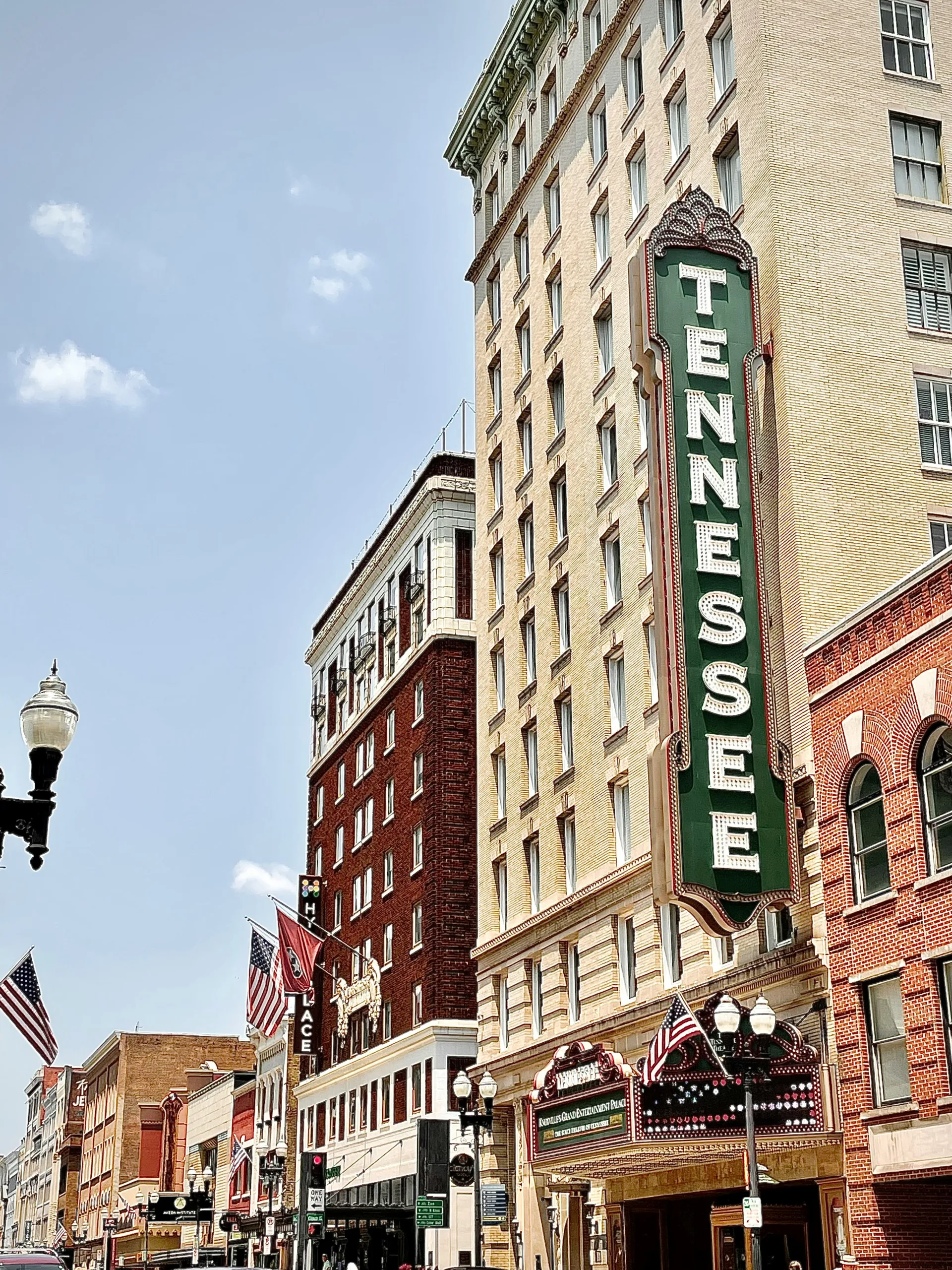 downtown-knoxville-maddie-burke-sWuplMpMPec-unsplash Historic Tennessee Theatre sign and buildings along Gay Street in downtown Knoxville, Tennessee, with American flags and pedestrians on a sunny day.